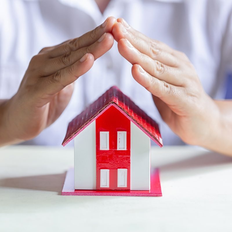 Mains protégeant une maison miniature