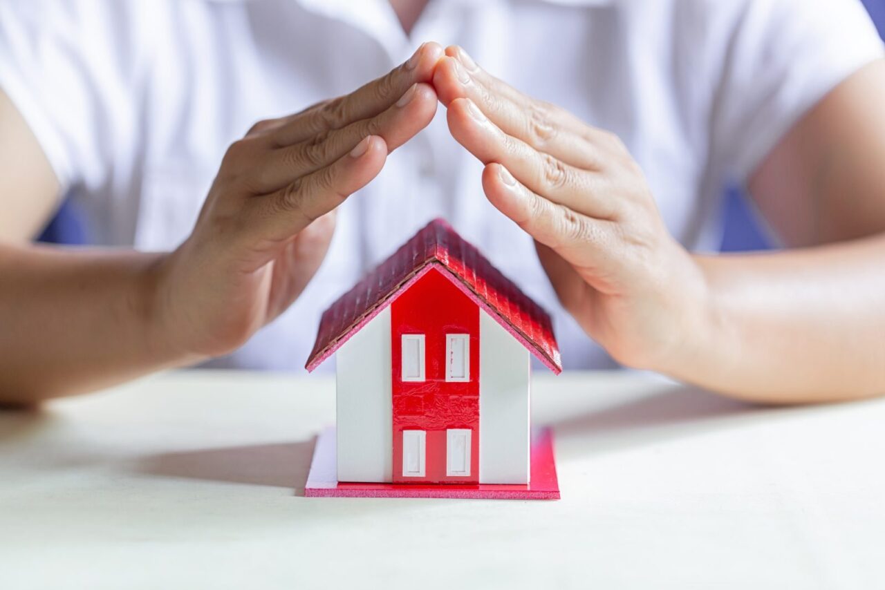 Mains protégeant une maison miniature