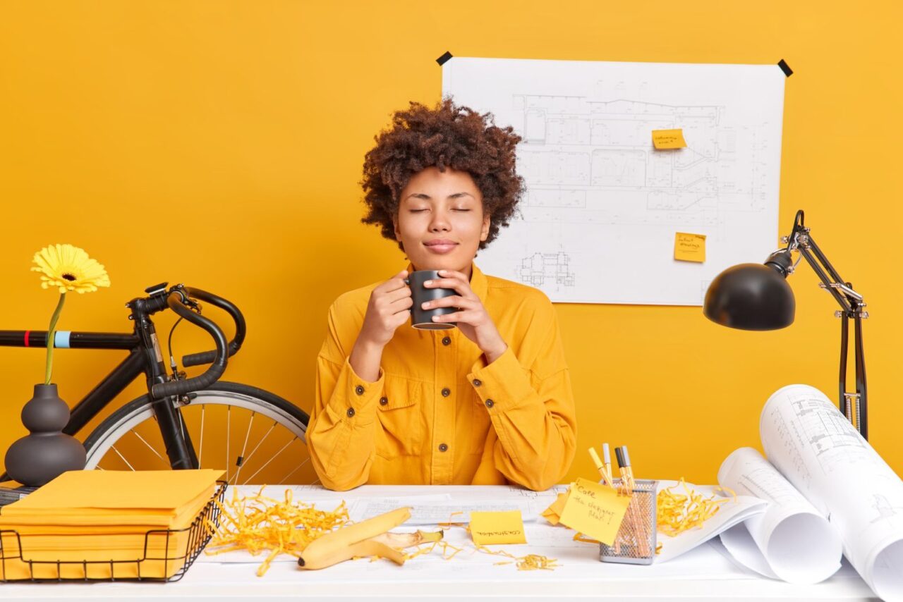 Collaboratrice détendue à son bureau, une tasse à la main